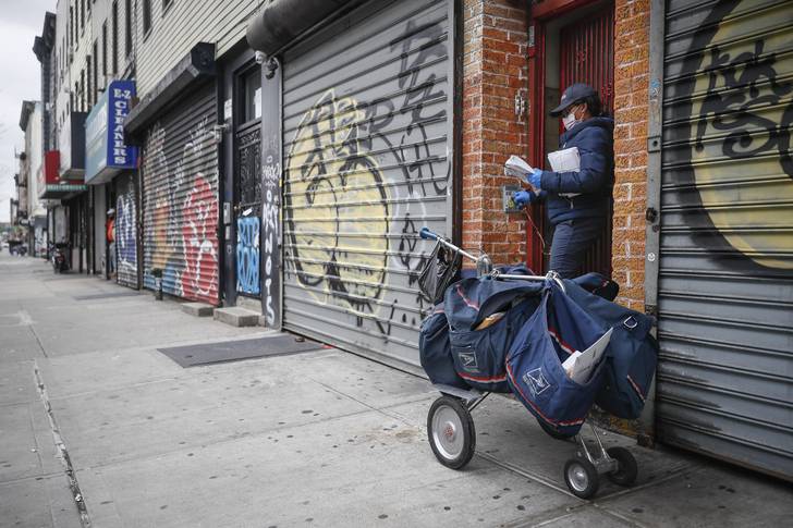 Postal worker delivers mail alongside shuttered storefronts as businesses remain closed due to social distancing protocols Brooklyn on April 27th.
